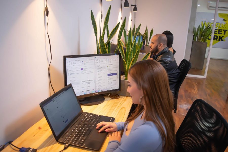 Three remote workers using laptops and monitors at a modern coworking space